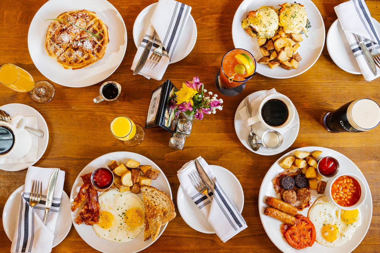 Full Irish breakfast, waffles and coffee laid out on a wooden table